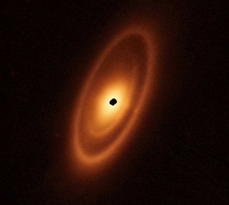 An orange oval extends from the 7 o’clock to 1 o’clock positions. It features a prominent outer ring, a darker gap, an intermediate ring, a narrower dark gap, and a bright inner disk. At the center is a ragged black spot where the detector is saturated.