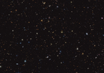 Thousands of small galaxies are scattered on a black background. Some are noticeably spirals, either face-on or edge-on, while others are blobby ellipticals. Many are too small to discern any structure. A few spirals are bluish, but most of the galaxies appear yellow or red. A handful of stars display eight-point diffraction spikes.