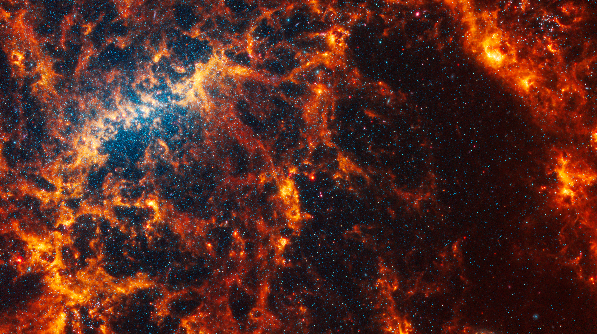 Webb’s image of NGC 5068 shows a portion of a messy face-on barred spiral galaxy in shades of white, yellow, orange, and red. The galaxy’s bar is a bright yellow arc-shaped region toward the center-left, and it is very difficult to see a spiral shape.