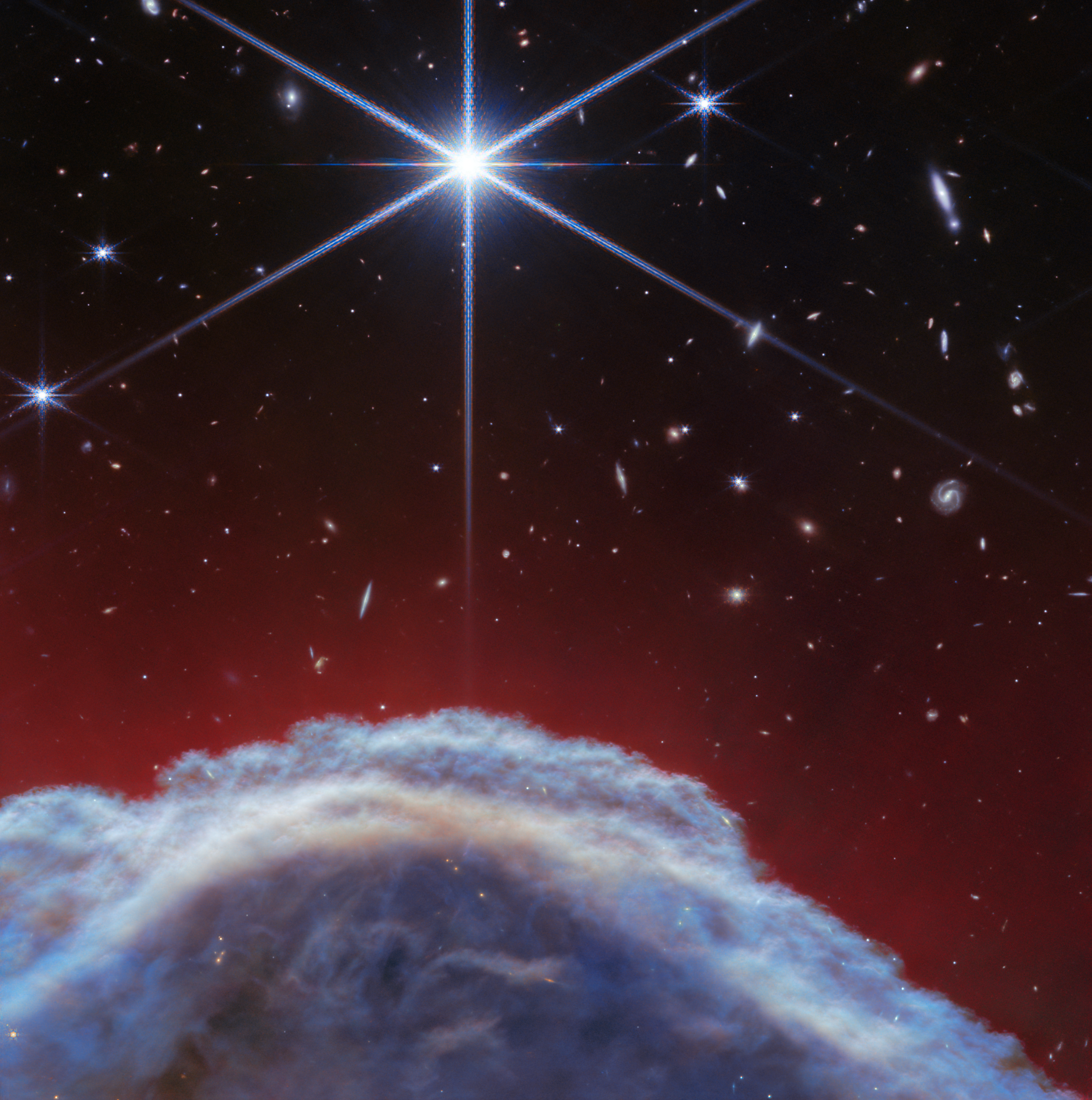 A clumpy dome of blueish-gray clouds topped with streaky, translucent red wisps. A large, prominent star is at the top of the image.