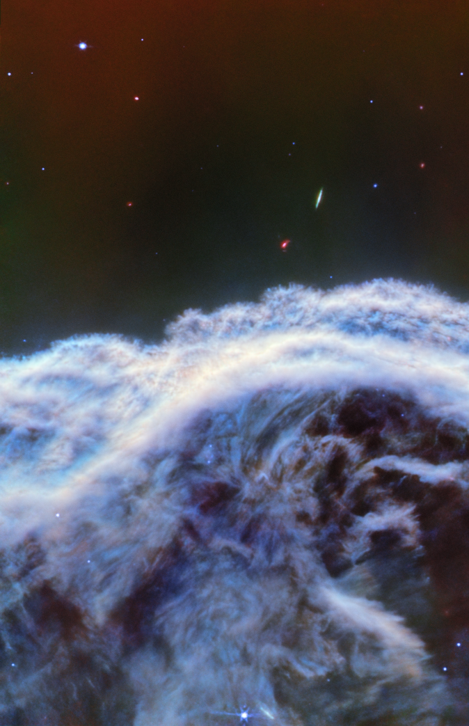 The image is more than half-filled from the bottom up by a small section of the Horsehead Nebula. Streaky clouds of white, gray and blue resemble a foamy wave crashing at the seashore. The nebula stops at a textured, fuzzy-looking edge that follows a slight curve. Above it a small number of distant stars and galaxies lie on a dark but multi-colored background.