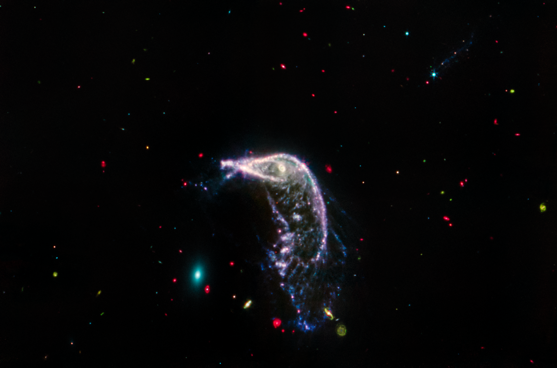 Two interacting galaxies known as Arp 142 in a horizontal image taken in mid-infrared light. At left is NGC 2937, which looks like a tiny teal oval and is nicknamed the Egg. At right is NGC 2936, nicknamed the Penguin, which is significantly larger and looks like a bird with a fanned tail.