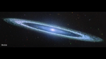 Image of a galaxy on the black background of space. The galaxy is a very oblong, blue disk that extends from left to right at an angle (from about 10 o’clock to 5 o’clock). The galaxy has a small bright core at the center. There is an inner disk that is clearer, with speckles of stars scattered throughout. The outer disk of the galaxy is whiteish-blue, and clumpy, like clouds in the sky. There are different colored dots, distant galaxies, speckled among the black background of space surrounding the galaxy.