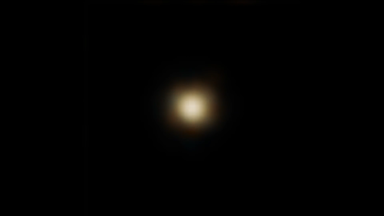 A mostly black image with a fuzzy yellow-white spot in the middle