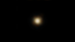 A mostly black image with a fuzzy yellow-white spot in the middle