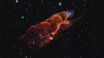 Angled from the upper left corner to the lower right corner is a cone-shaped orange-red cloud known as Herbig-Haro 49/50. This feature takes up about three-fourths of the length of this angle. The upper left end of this feature has a translucent, rounded end. The conical feature widens slightly from the rounded end at the upper right down to the lower right. Along the cone there are additional rounded edges, like edges of a wave, and intricate foamy-like details, as well as a clearer view of the black background of space. In the upper left, overlapping with the rounded end of Herbig-Haro 49/50, is a background spiral galaxy with a concentrated blue center that fades outward to blend with red spiral arms. The background of space is speckled with some white stars and smaller, more numerous, fainter white galaxies throughout.