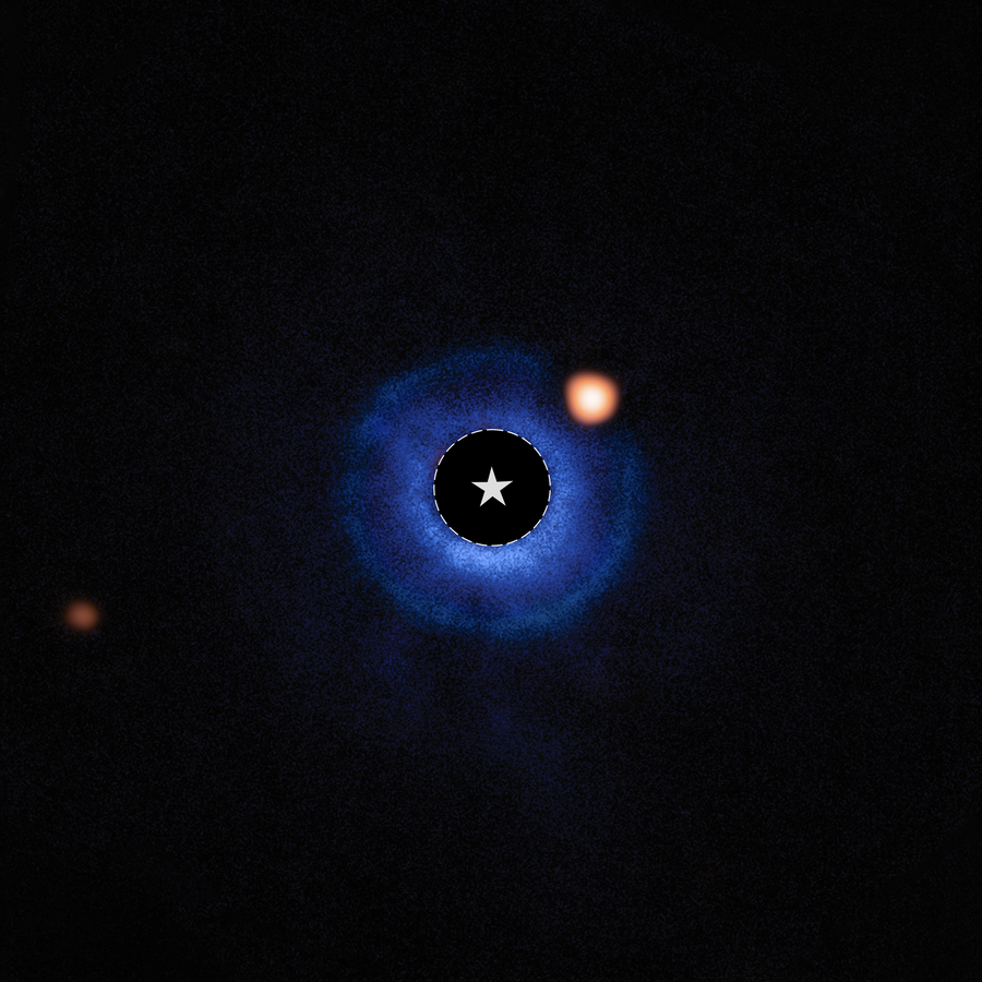 An image of a nearby star and its vicinity. The star itself has been blocked out and its bright light has been removed, appearing black. A dashed circle with a star symbol at the center of the image marks the star’s location. A fuzzy blue disk surrounds the star. An orange spot, near the star and inside this disk around 2 o’clock, is identified as a planet orbiting the star. A fainter orange spot at the lower left edge marks a distant star.