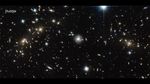 Hubble observation of the Bullet Cluster shows many overlapping objects, including foreground stars, galaxies in galaxy clusters, and distorted background galaxies behind the galaxy clusters. The objects are all at various distances set against the black background of space.