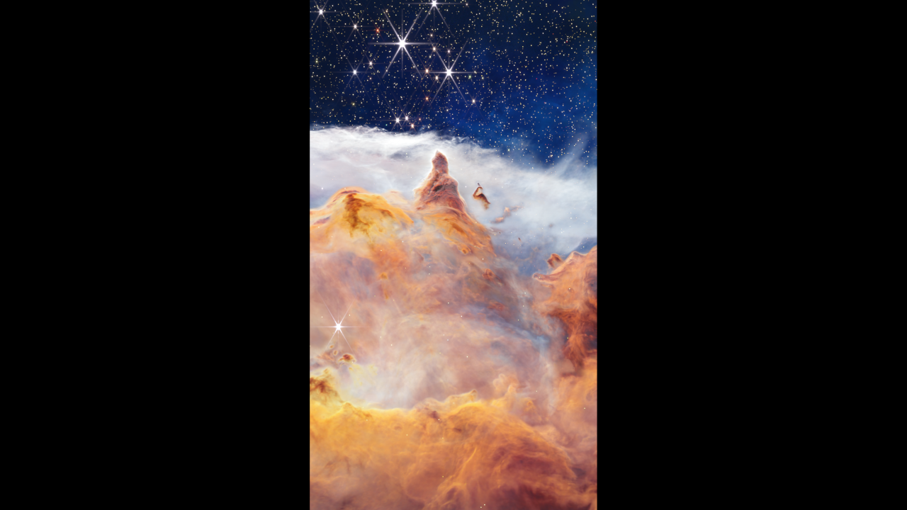 In what appears as a celestial dreamscape, a blue and black sky filled with brilliant stars covers the top quarter of the image. The stars are different sizes and shades of white, beige, yellow, and light orange. Near the middle of the field, the two largest stars are white with six-pointed diffraction spikes. Across the bottom quarter of the scene is a craggy, mountain-like vista with a spire-like peak pointing toward those two largest stars. The so-called mountain appears in varying shades of orange, yellow, and brown. A wispy, ethereal white cloud stretches  across the scene, separating the apparent mountain from the blue and black sky.