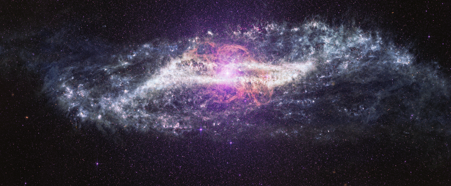 A horizontal image of the galaxy Centaurus A stretches across a black background filled with thousands of tiny purple, pink, and white points of light. The galaxy is brightest at its center, where a brilliant white and pale pink glow radiates outward. Eight diffraction spikes extend from the central glow. Delicate loops and wispy ribbons of pink and lavender arc above and below the center of the image in the shape of an ‘S’. A band of gray and white dust in the shape of a parallelogram cuts across the middle of the galaxy. Mottled patches and bright knots are scattered throughout the dusty band. The galaxy’s outer edges fade into soft, cloud-like plumes with feathery textures that stretch toward the left and right sides of the image. Against the surrounding darkness, a few bright foreground stars shine with Webb’s distinctive diffraction spikes, while countless fainter stars create a speckled backdrop.