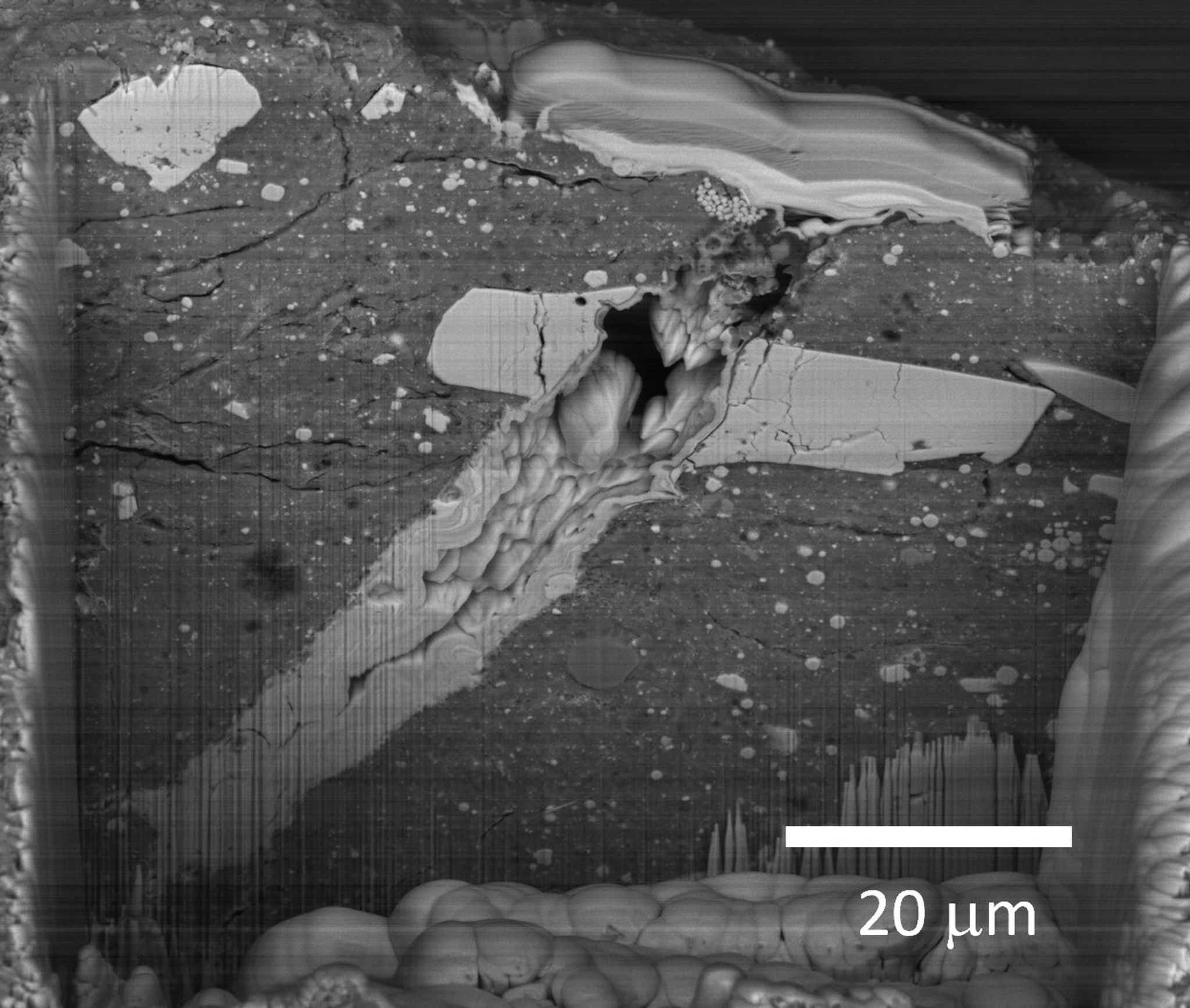 A scanning electron microscope image of a micrometeorite impact crater in a particle of asteroid Bennu material.