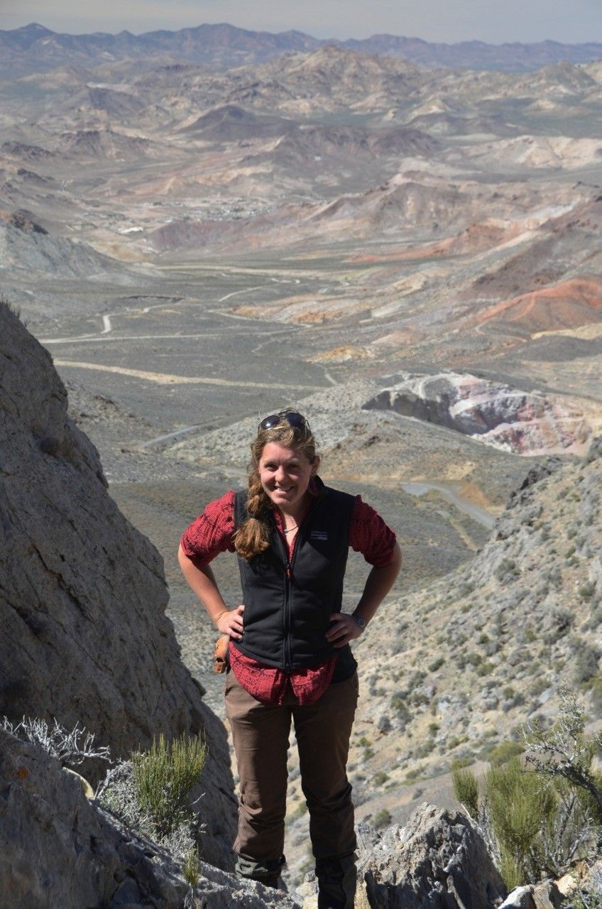 Woman on a mountain in Nevada with a valley behind her.