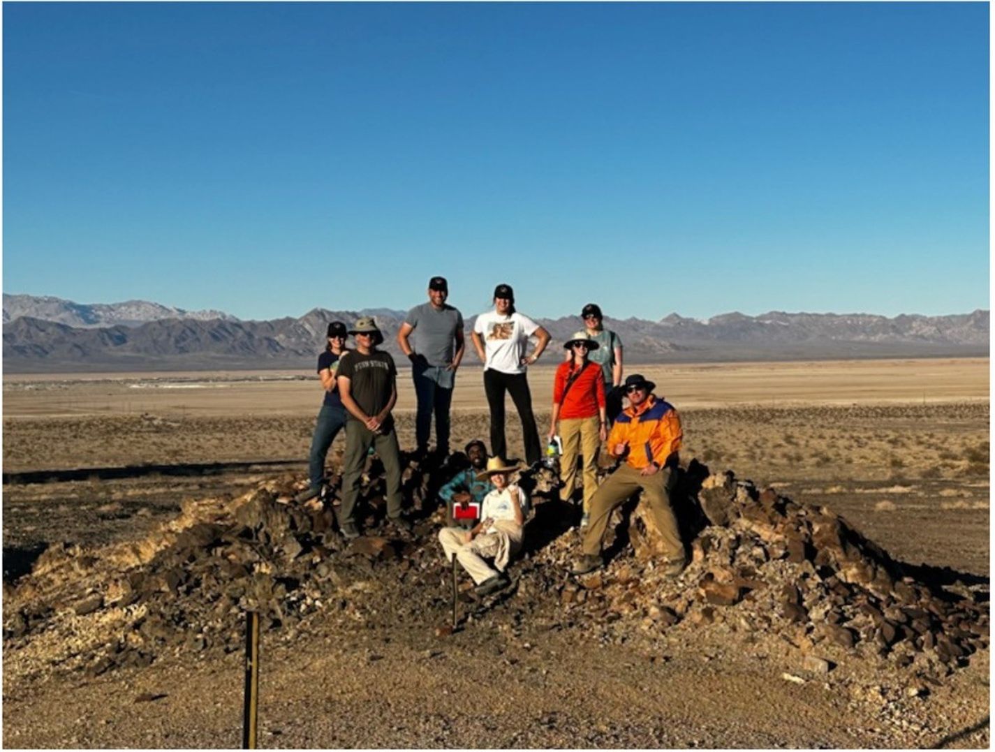 A group of people standing on a hill in the desert.