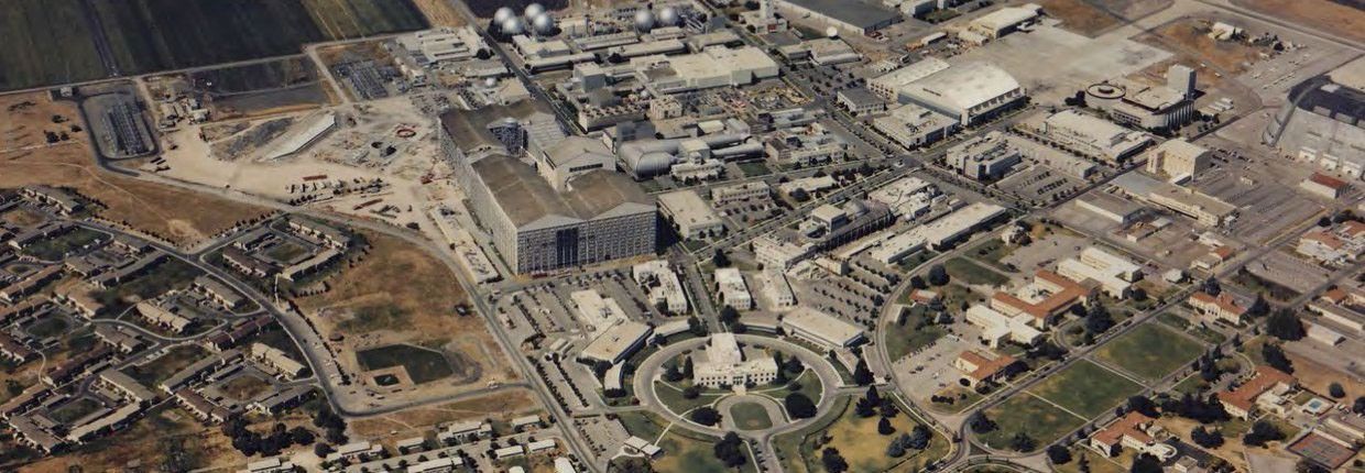 An aerial view of the NASA Ames Research Center in Mountain View, California.  It shows a collection of buildings and sweeping roads between them. The grass is quite brown, indicating it is the dry season.
