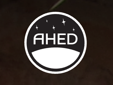 The logo is a white circle enclosing a dark blue/black circle. At the bottom of the circle is a white crescent representing the horizon of a planetary surface. In the dark space above are stars. The letters AHED are against the dark background in white.