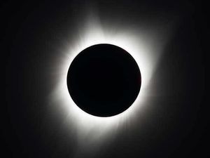 A black circle surrounded by a white, smudgey, streaky halo showing the Moon blocking the Sun during an eclipse.