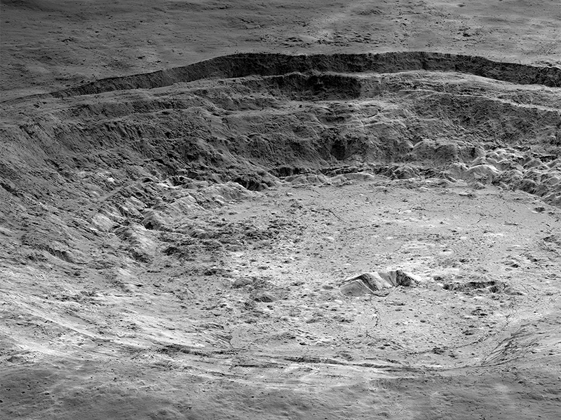 Low-angle orbital view of a crater with concentric levels inside, like an amphitheater.
