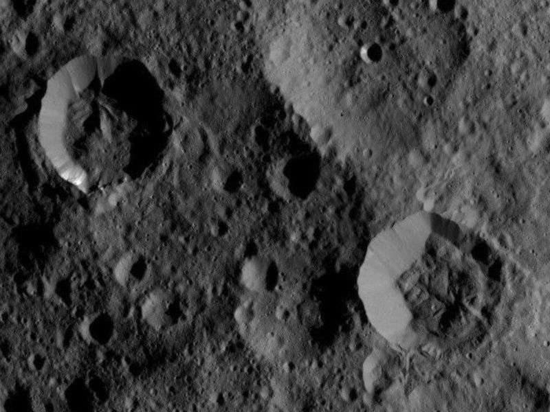 Overhead view of craters in grey lunar terrain.