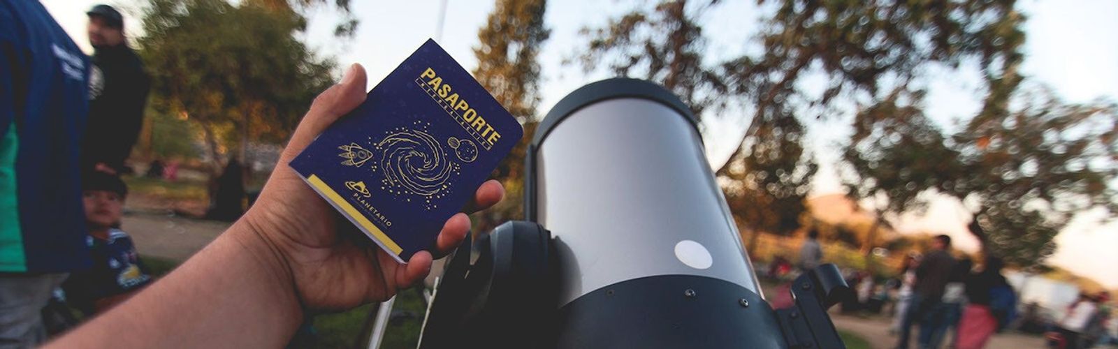 Hand holding a passport next to a telescope