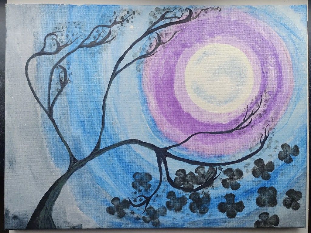 A white Moon is painted on a bluish gray background, with rings of color surrounding the Moon. The thin branches of a tree stretch upwards towards the Moon. Black flowers speckle the lower right portion of the painting.