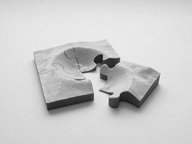 A grey four-piece jigsaw puzzle is shown with one of the pieces loose.
