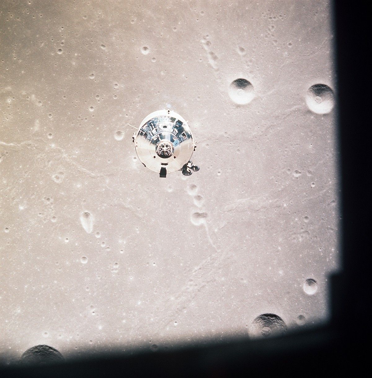 reflective metal spacecraft above the cratered lunar surface