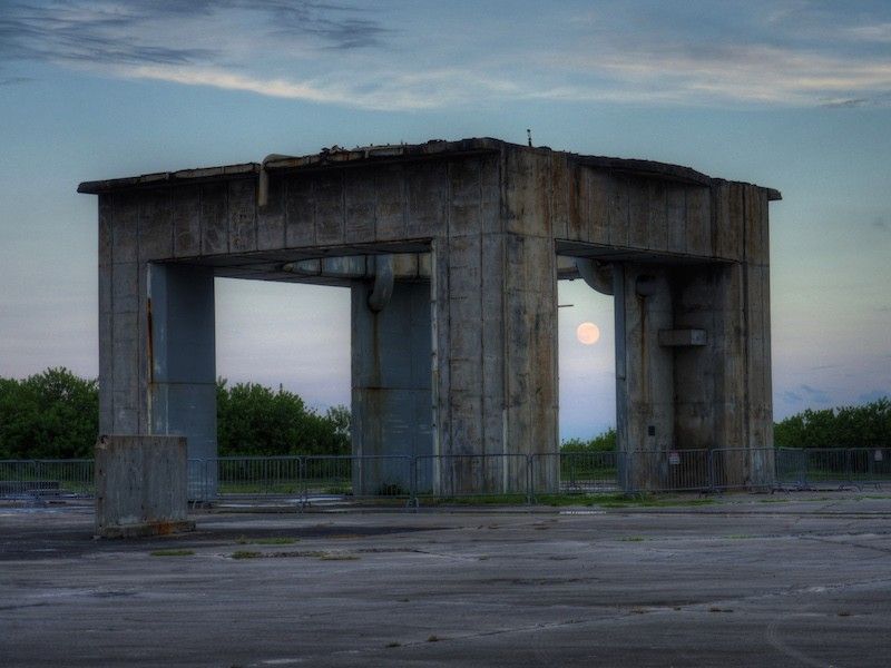 Moon rising, seen through gaps in a concrete structure