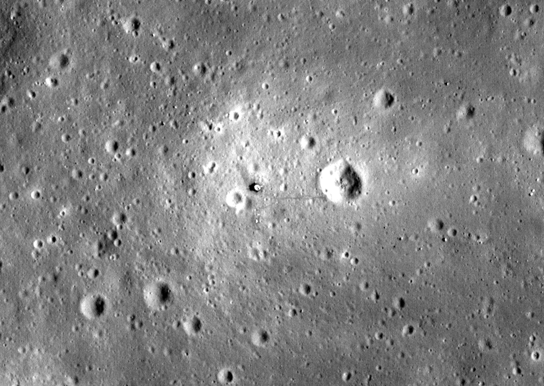 Black and white image of the Moon from orbit with small lines showing path walked by Apollo 11 astronauts.