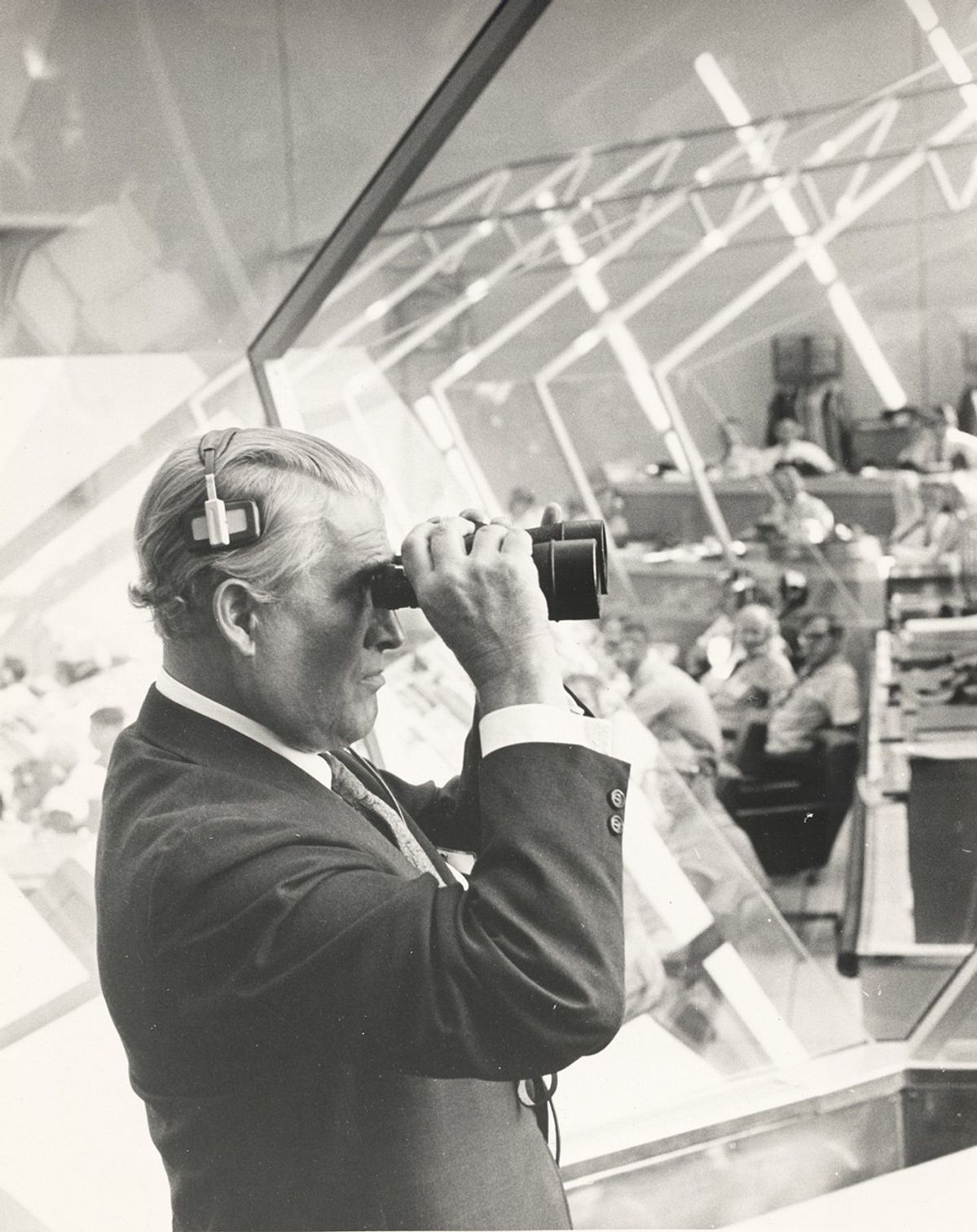 Man wearing formal suit and looking through binoculars, indoors