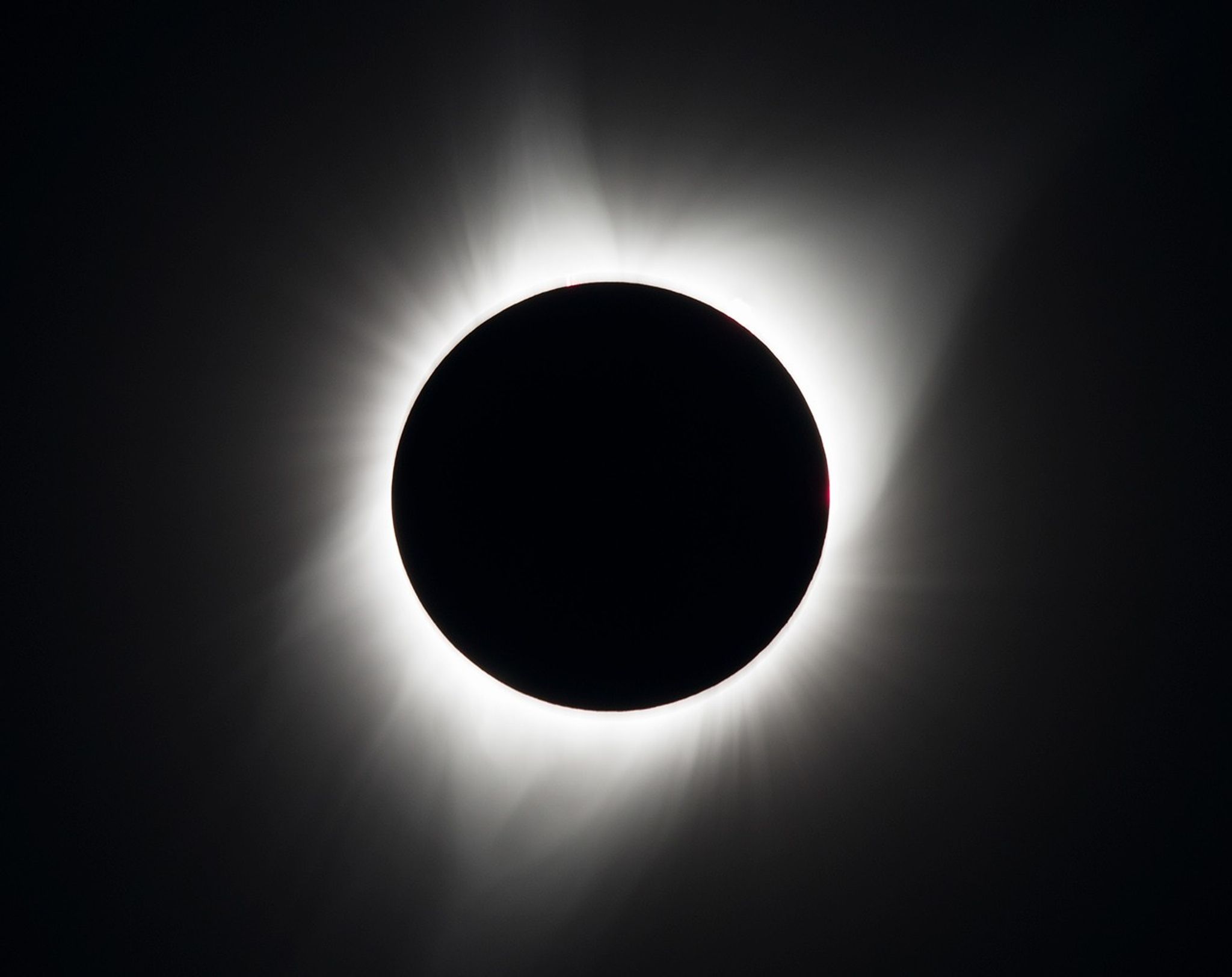 Sun blocked by Moon in total eclipse, with just the solar corona visible as a glow around the silhouetted Moon