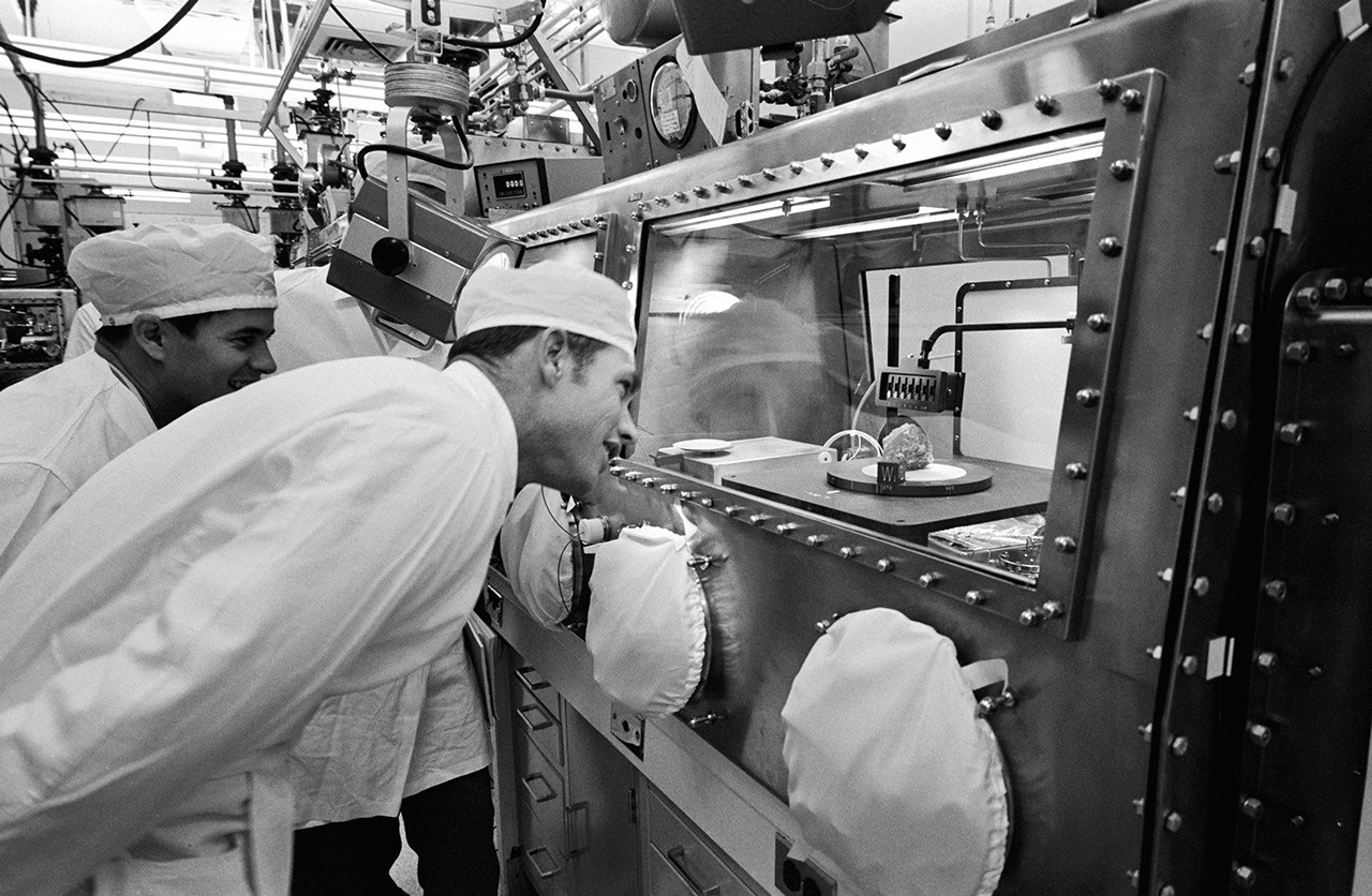 Black and white image of man looking into sterile sample containment unit.