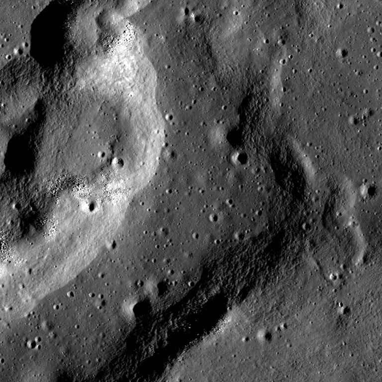 Overhead view of a pockmarked landform on the Moon. Light catches the curved edge of the ridge on the left; its right edge is in shadow.