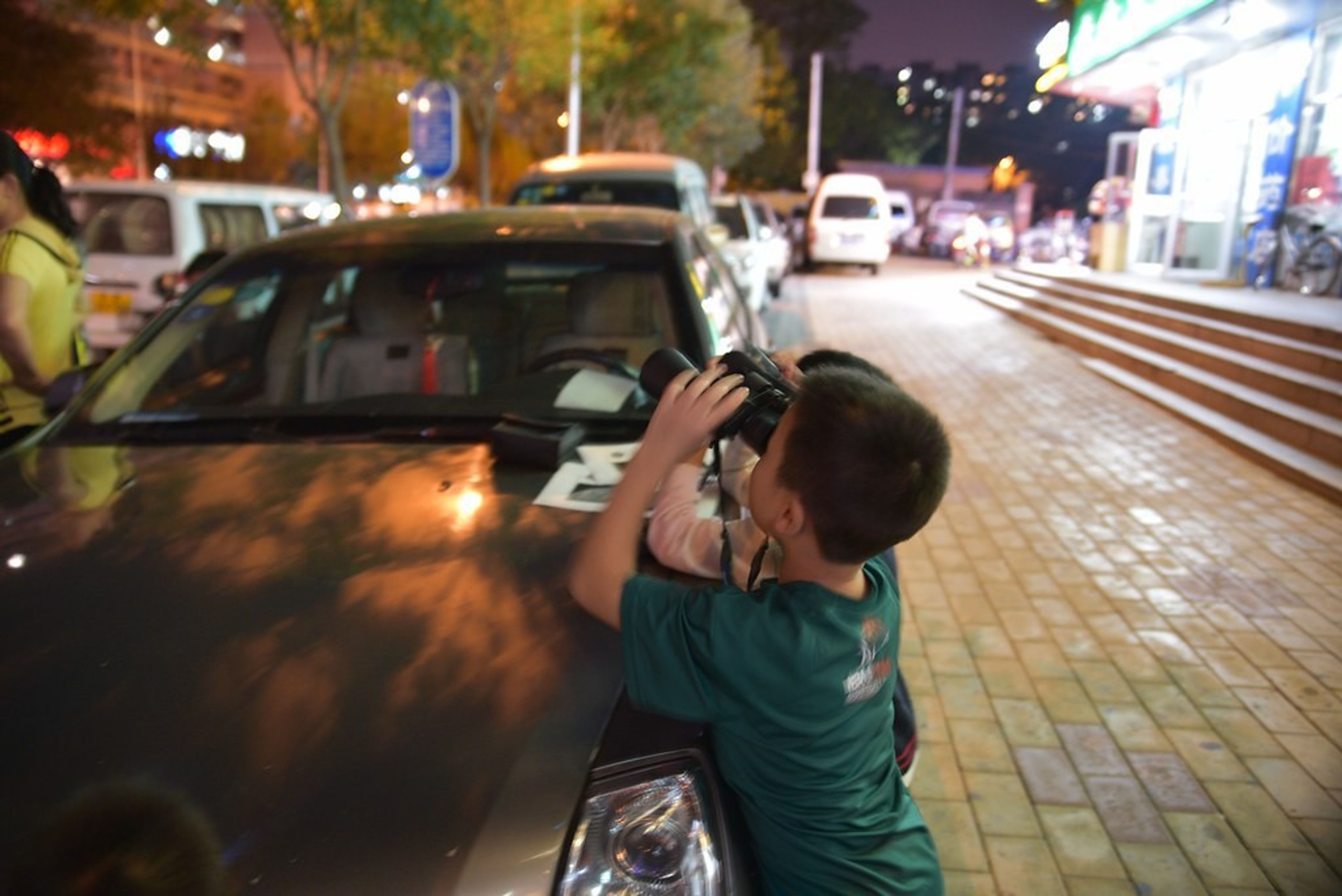 Child looking through tripod-mounted binoculars.