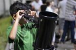 Un niño mira el cielo través de un telescopio. 