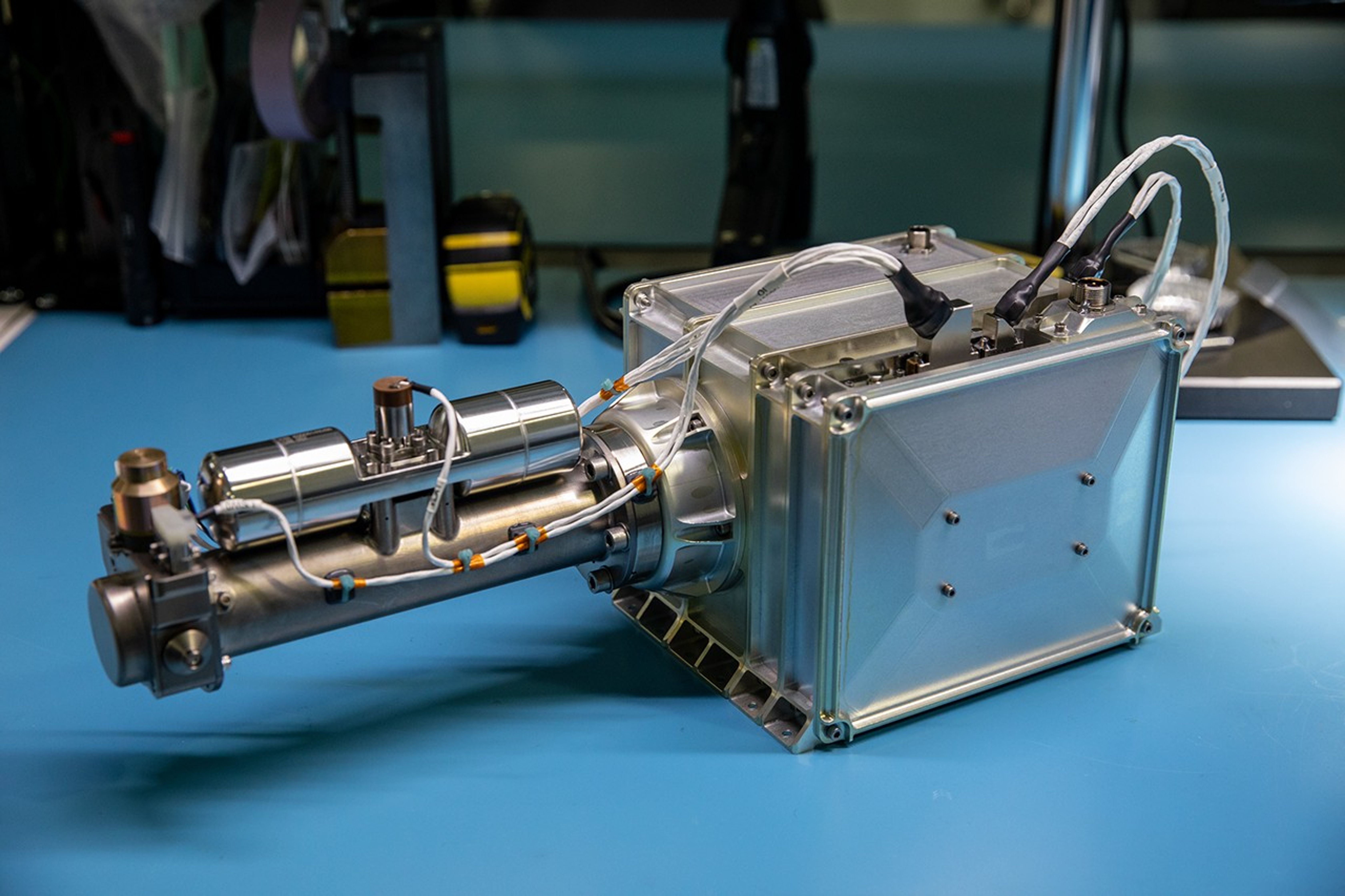 The MSOLO instrument sits on a lab table. It consists of a primary box with a long metallic arm coming out of the side, with various wires and other electronics present all around.