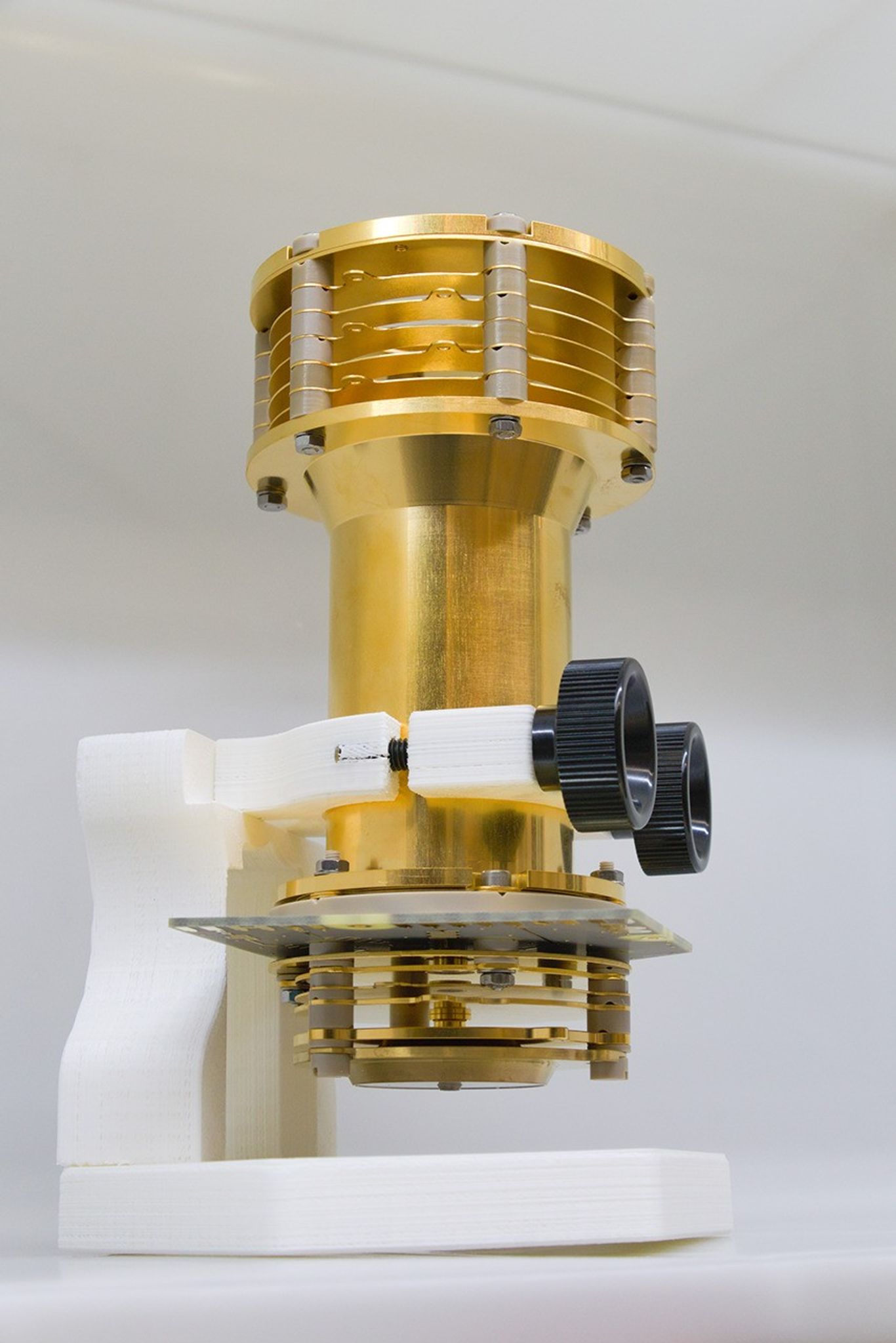 A semi-cylindrical bronze-appearing column mounted vertically on an adjustable stand in a lab.