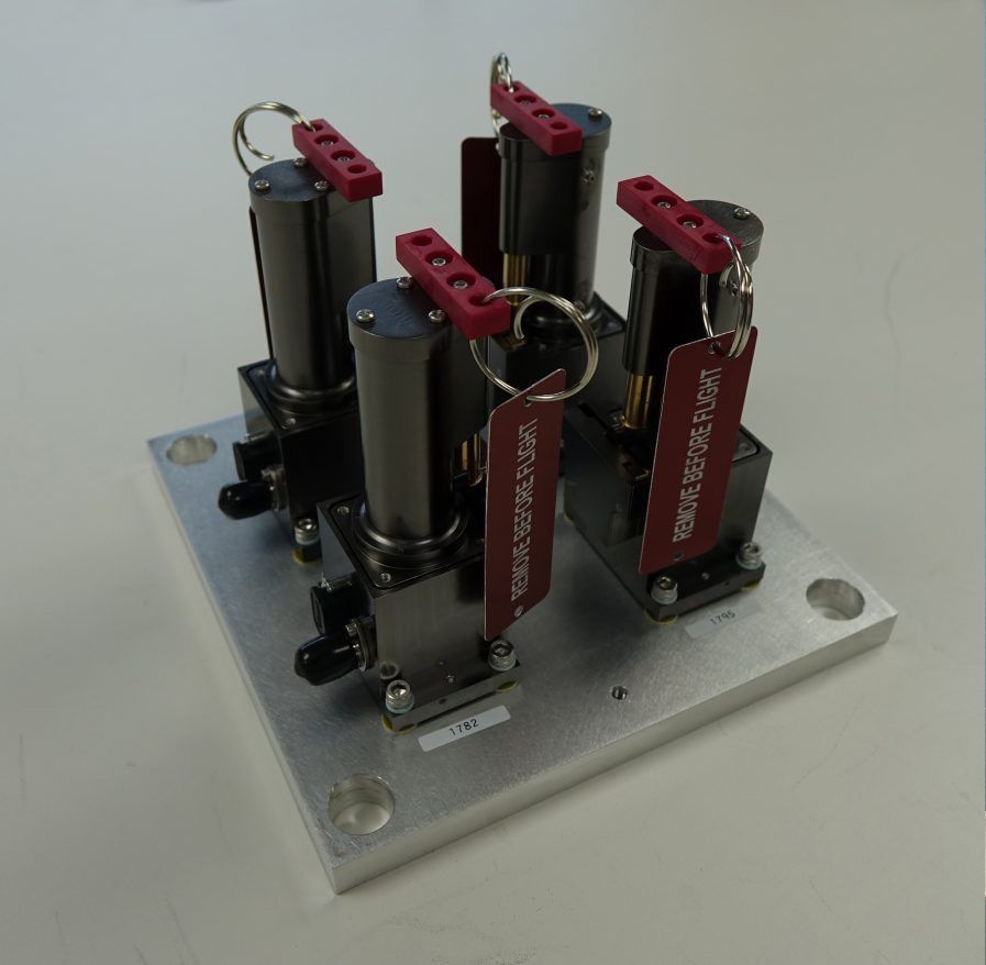 4 small cylindrical glassy antenna columns are mounted upright in a square on a mounting board.
