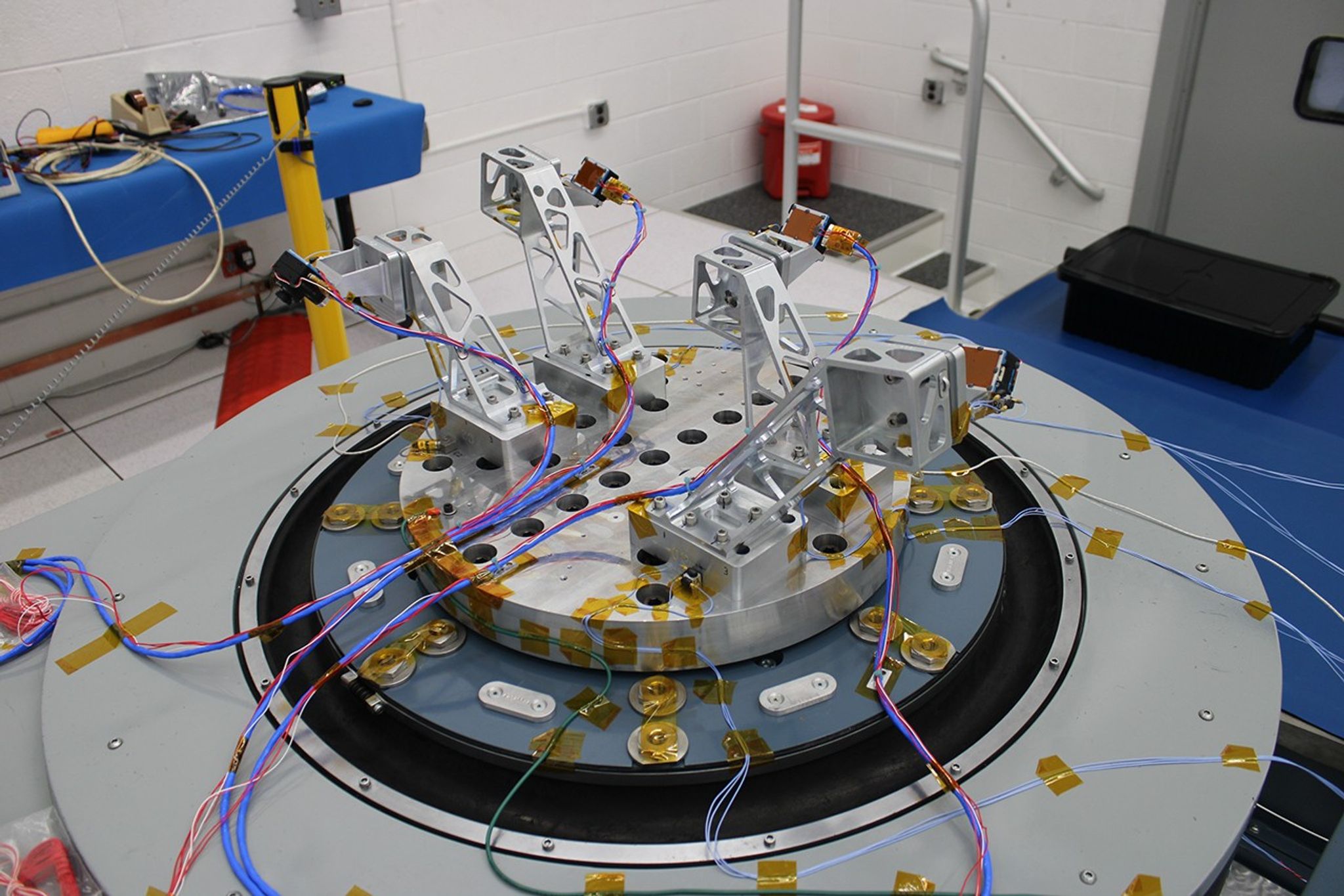 The SCALPSS 1.x assembly system is mounted on a table in a lab for testing. It's a circular metal plate with metal mounts for 4 different cameras oriented in different directions.