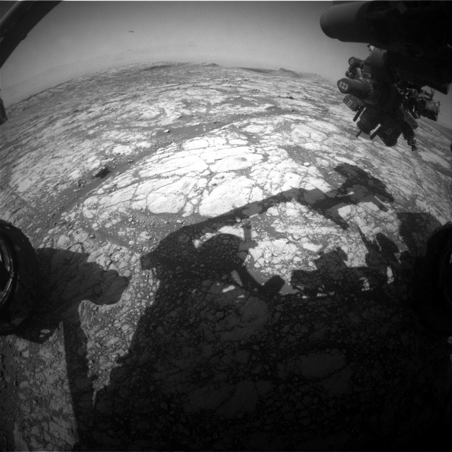 The shadow of Curiosity’s arm is visible against Mars' surface