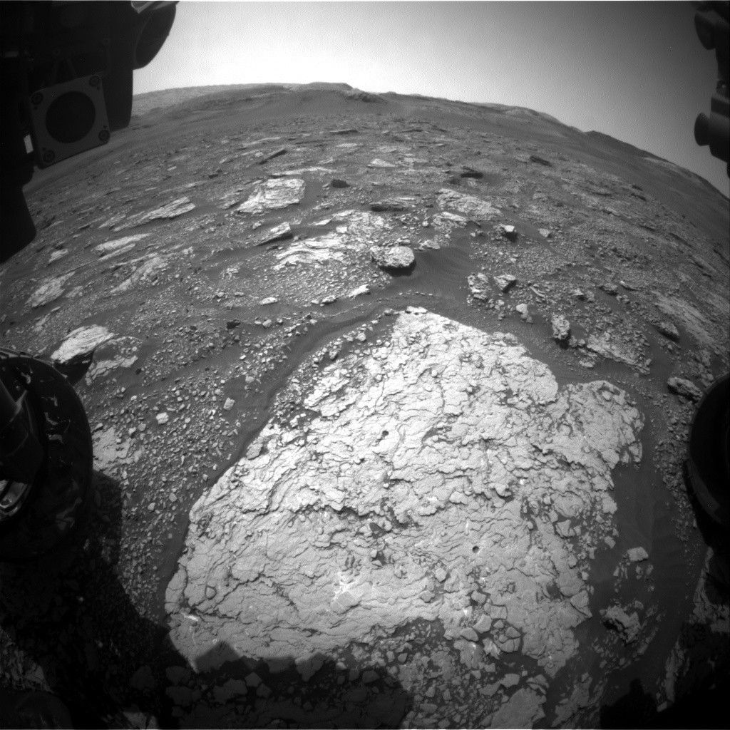 An imaging of the front work space of the Curiosity rover on Mars with drill holes in the ground.
