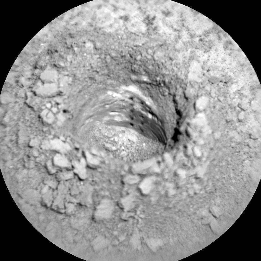 This is a black and white image of the Gordon drill hole after the second LIBS analysis. The image was taken through a circular lens and shows a rocky surface surroubnding the hollow hole made by the Gordon drill.