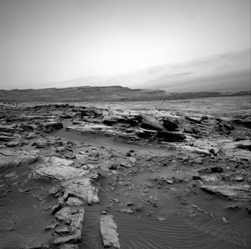 The rocks in the immediate foreground are the lowermost capping unit, with the pediment surface extending beyond. The large-scale layered ridge in the distance is the Gediz Vallis ridge, with Gale crater rim in the background.
