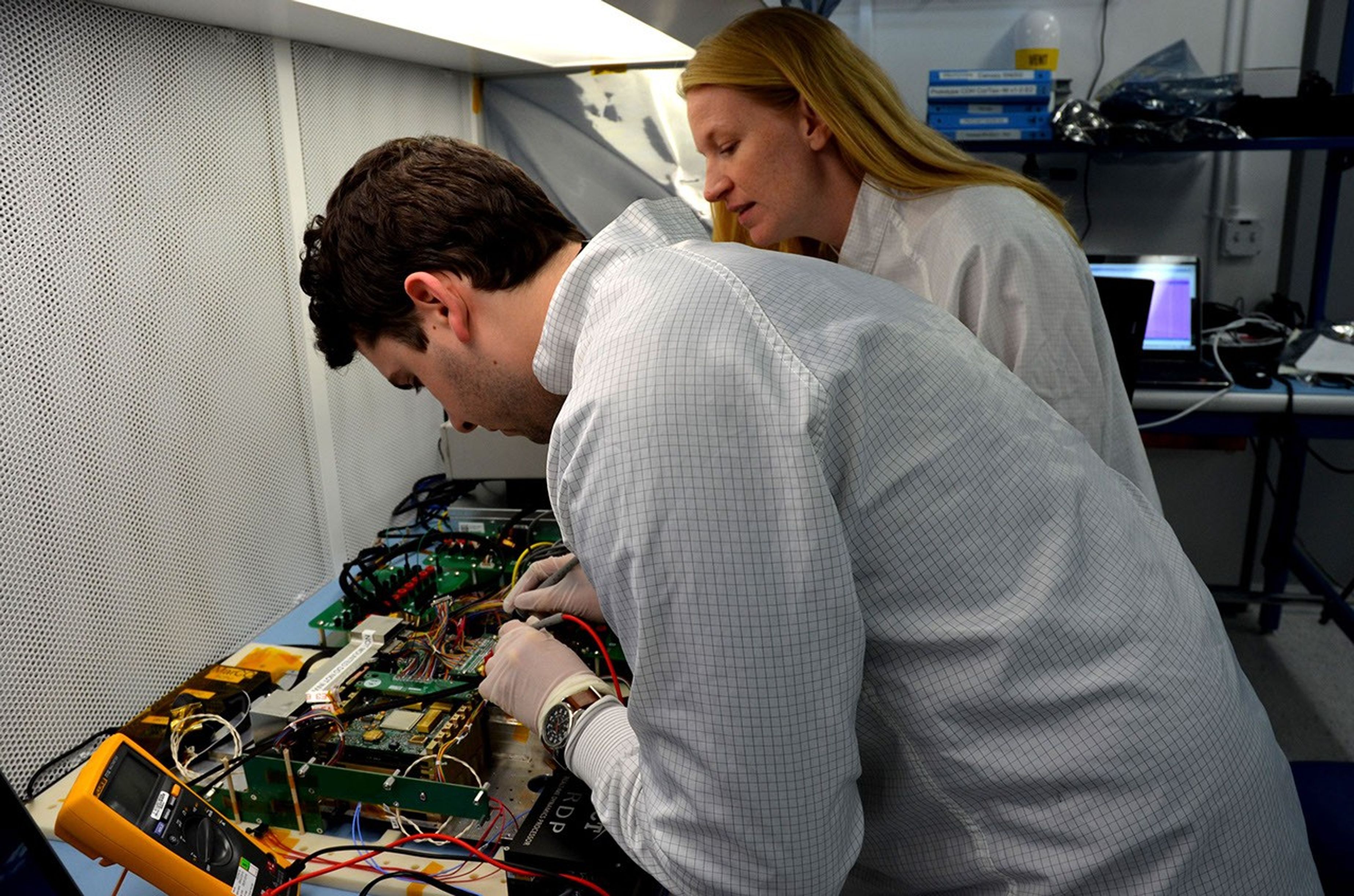 Engineers for NASA's MarCO (Mars Cube One) technology demonstration inspect the MarCO test bed, which contains components that are identical to those built for a flight to Mars. Cody Colley, left, MarCO integration and test deputy, and Shannon Statham, MarCO integration and test lead, are on the team at NASA's Jet Propulsion Laboratory, Pasadena, California, preparing twin MarCO CubeSats.