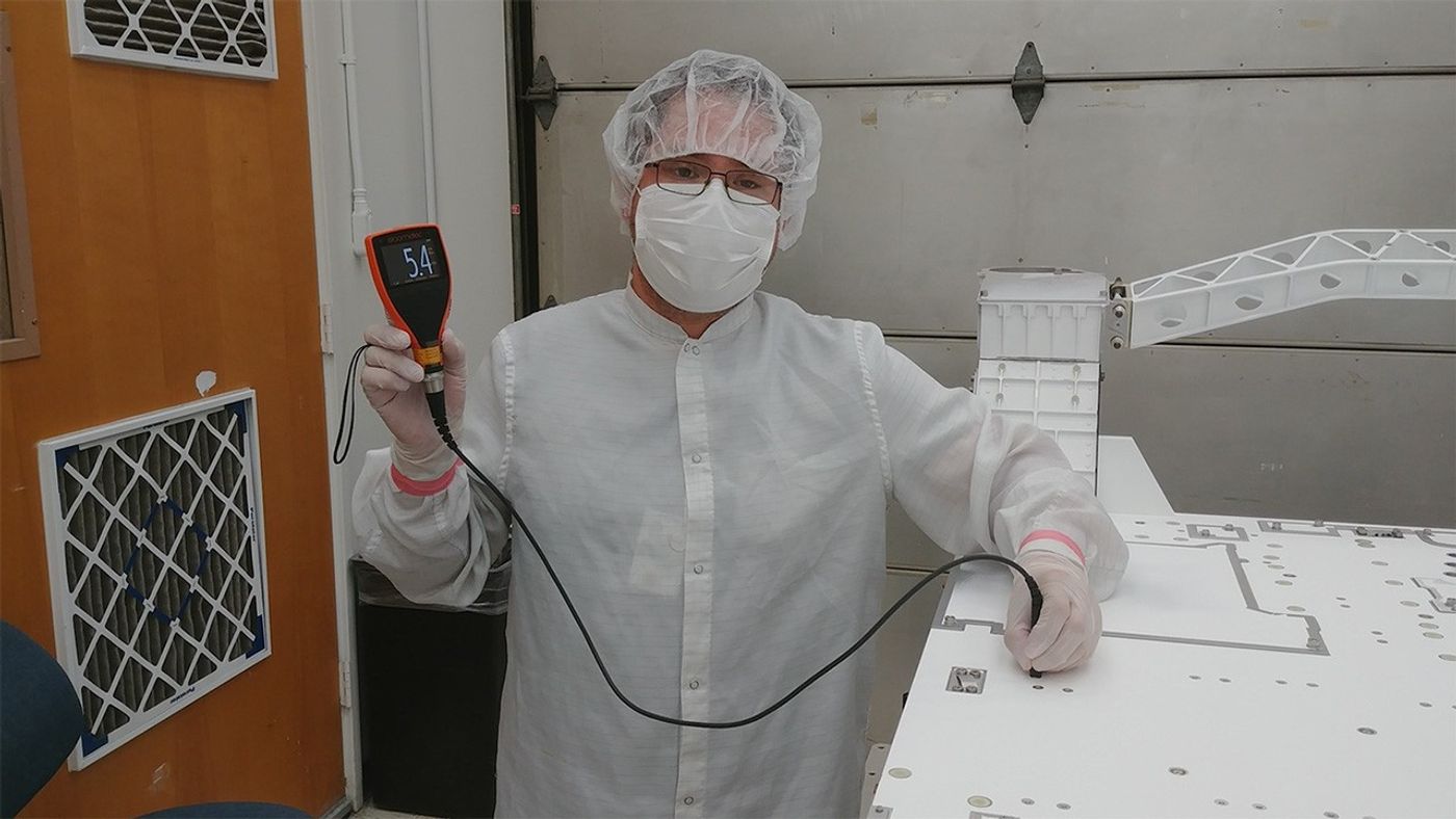 JPL mechanical technician Eddie Castro uses a paint meter to measure the paint thickness on the Mars 2020 rover chassis.
