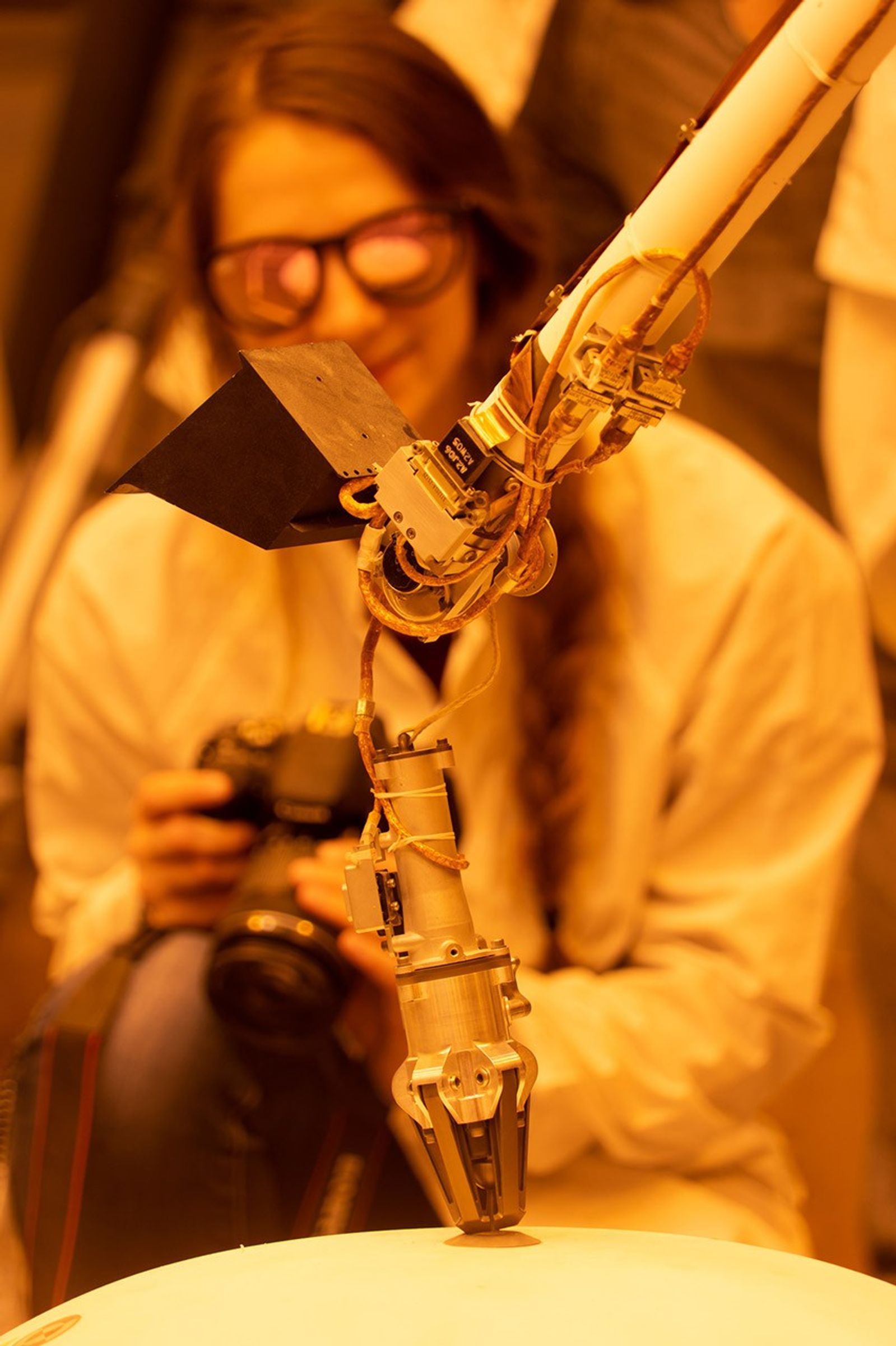 ForeSight, a fully functional, full-size model of NASA's InSight lander, grasps a model of the lander's Wind and Thermal Shield while engineer Maggie Williams looks on. This testing was done at NASA's Jet Propulsion Laboratory in Pasadena, California.