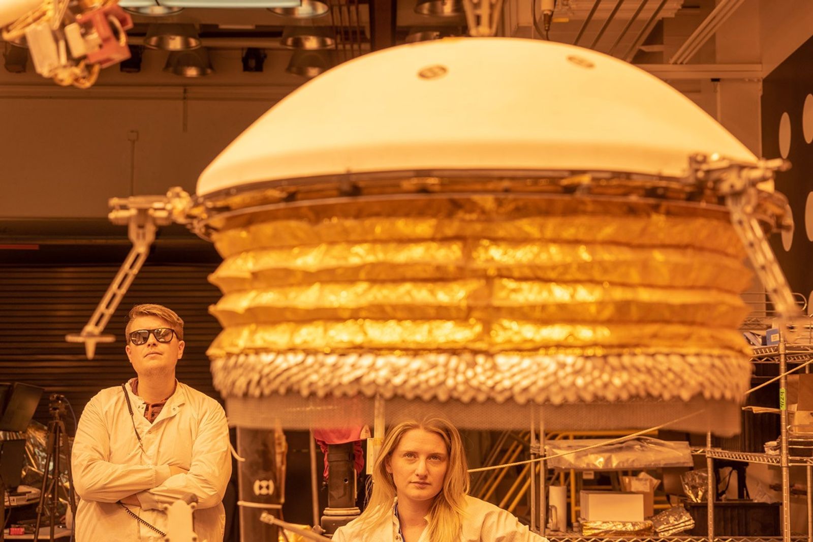 ForeSight, a fully functional, full-size model of NASA's InSight lander, practices deploying a model of the lander's Wind and Thermal Shield while engineers Phil Bailey (left) and Jaime Singer (center) look on. The Wind and Thermal Shield protects InSight's seismometer. This testing was done at NASA's Jet Propulsion Laboratory in Pasadena, California.