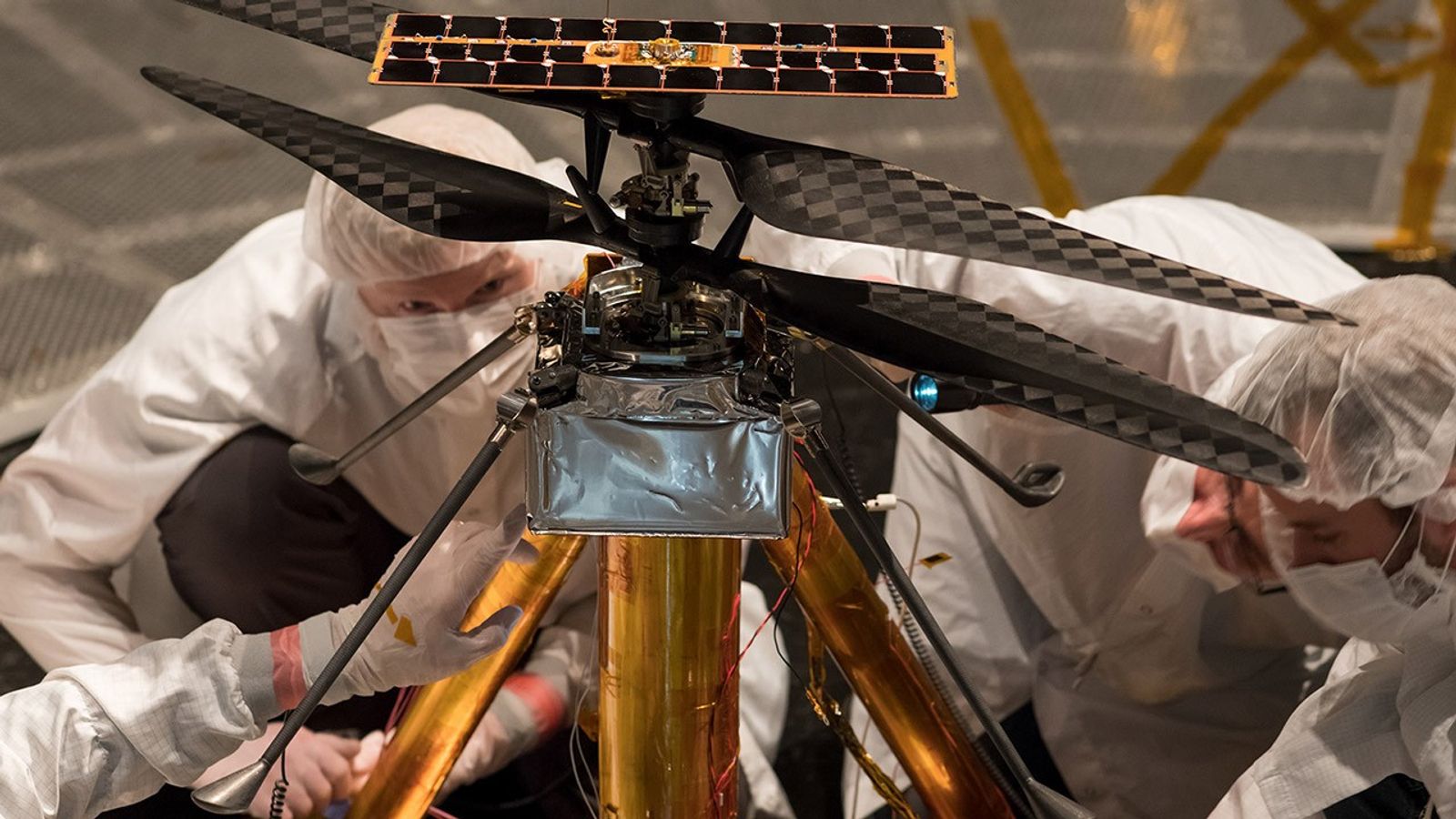 Members of the NASA Mars Helicopter team inspect the flight model (the actual vehicle going to the Red Planet), inside the Space Simulator.