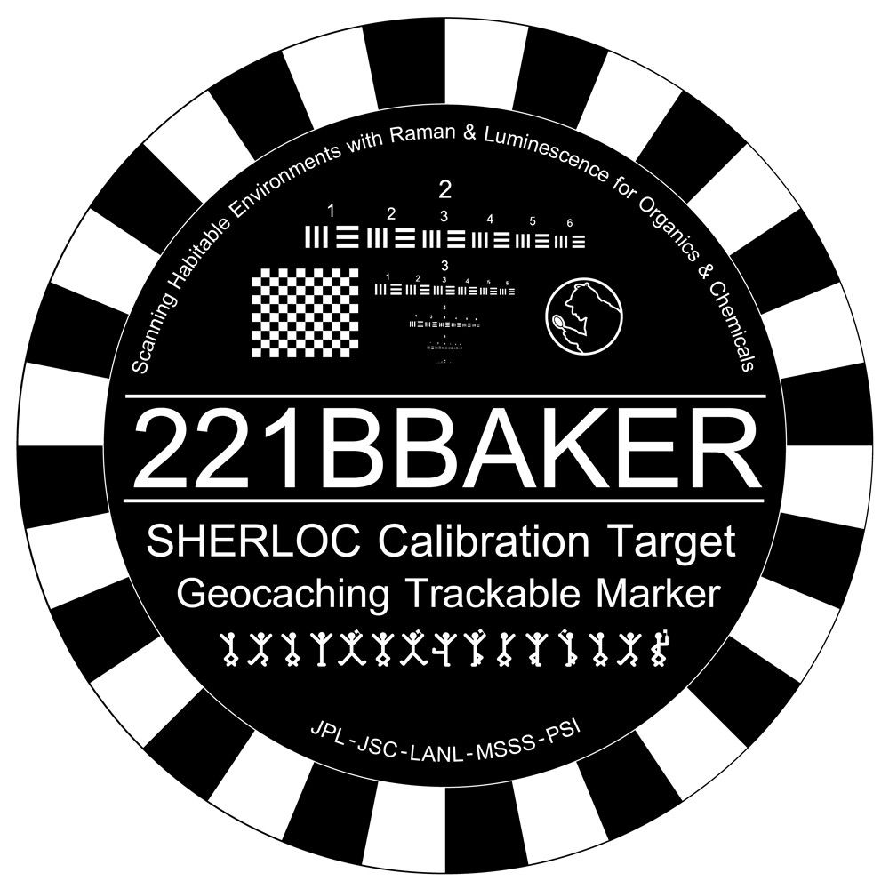 A round coin with a striped border, with letters and symbols to assist in adjusting the SHERLOC instrument.