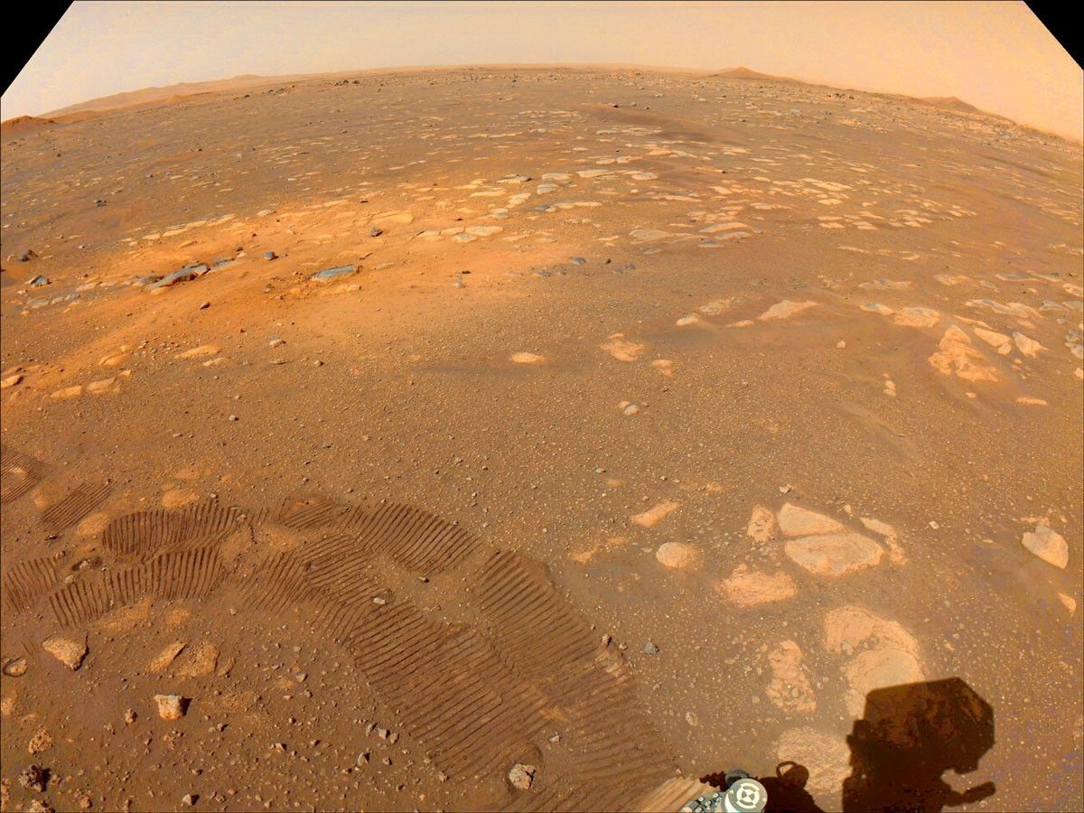Taken on March 5, 2021, this color-calibrated image from a Navigation Camera aboard NASA’s Mars 2020 Perseverance rover shows tracks from the rover’s first drive (darker marks in the foreground) and an area scoured by the Mars 2020 mission’s descent stage rockets (lighter-colored area in the middle ground).