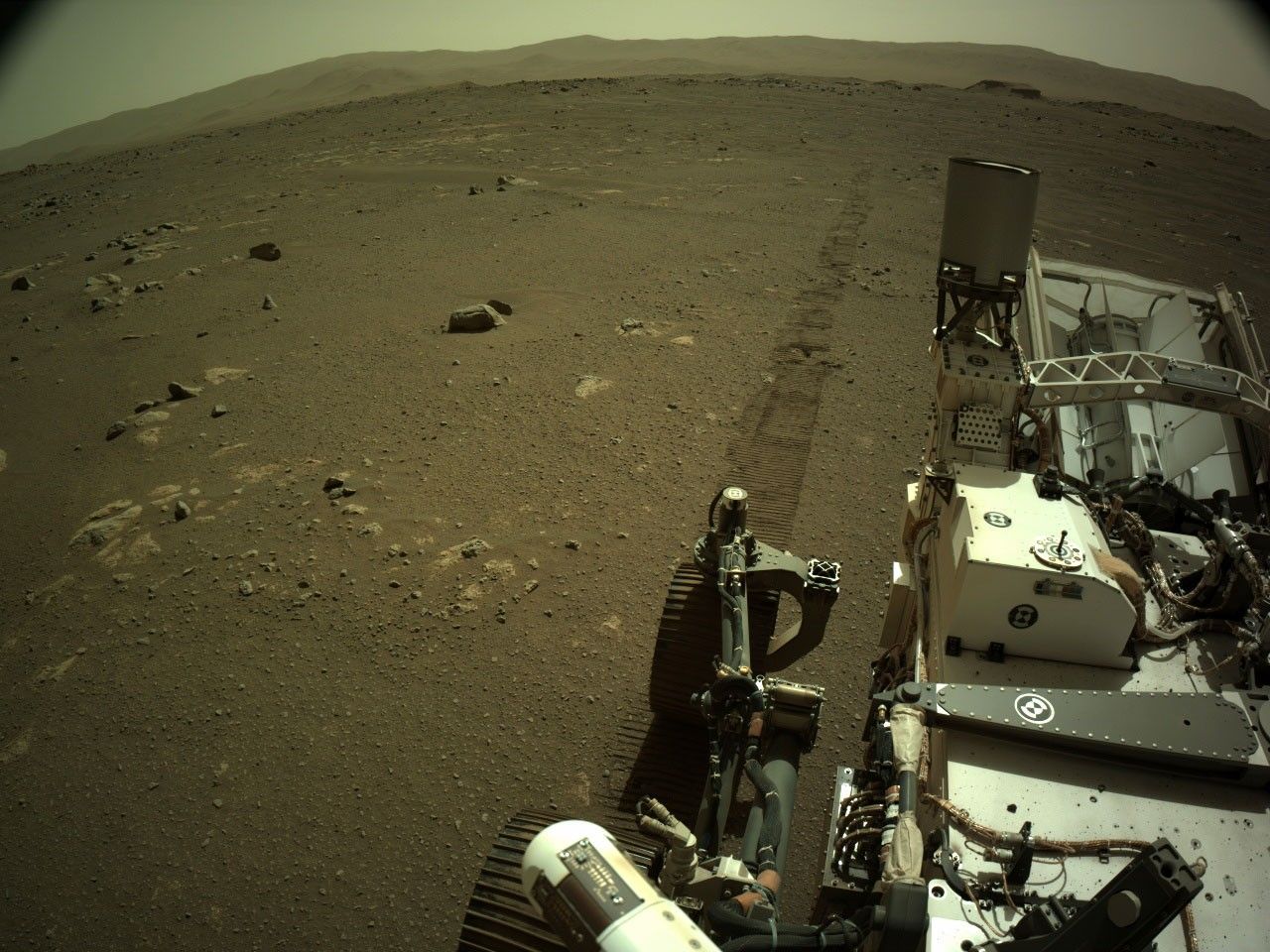 Image taken by Perseverance after driving with rover tracks behind it.
